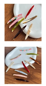 Detail of assorted acetate hair clips with gold metal spring on a ceramic display plate