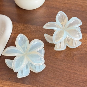 Eleganter hellblauer Blumen-Haarclip mit mattem Finish auf dunkler Holzoberfläche