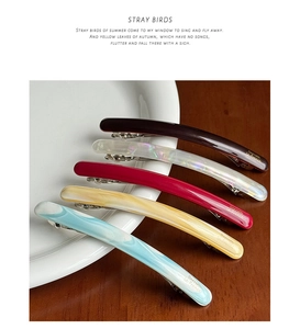 Detailed close-up of acetate barrette hair clips in five colors with marble texture