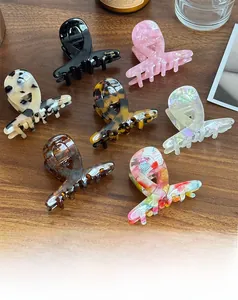 Detail of medium acetate claw clips in diverse patterns on a wooden surface