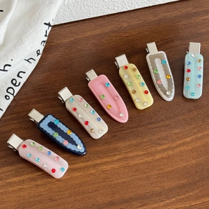 Set of 8 colorful rhinestone acetate hair clips with metal duckbill grips on wood