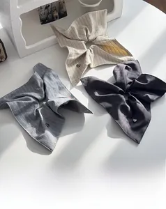 Detail of striped fabric scrunchies in beige and grey with tiny silver heart charms