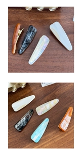 Macro detail of tortoiseshell and marble acetate hair clips on dark wood background
