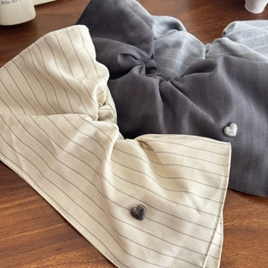 Three striped fabric scrunchies with heart metal charms on a wooden surface
