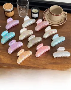 Detailed view of starfish hair claws in pearlescent pastel colors on a wooden table