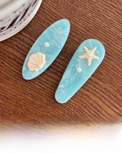 Detail of light blue marble hair clip with seashell and starfish ocean theme