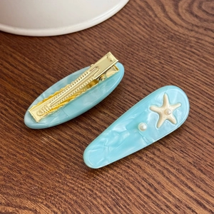 Blue marble acetate starfish hair clips with pearls on dark wood background