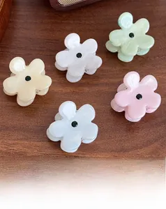 Detail von fünf bunten Blumen-Haarklammern mit Strasssteinen auf einem Holztisch