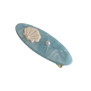 Elegant blue sea-style hair clip with shell and pearl decoration on white background
