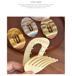 Macro shot of large matte hair claws in various colors on a wooden tray decor