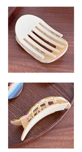 Detail view of large beige matte hair claw clip with floral pattern and metal spring