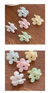 Detail von Mini-Blumen-Haarklammern in Pastellfarben mit Perlmuttglanz auf Holzoberfläche