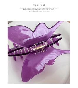 Dettaglio di un fermaglio per capelli a farfalla viola con glitter fini ed emblema oro