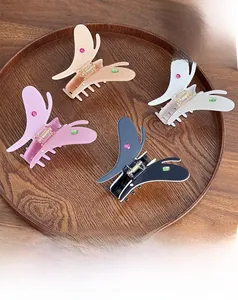 Lot de quatre pinces à cheveux papillon avec strass présentées sur un plateau en bois
