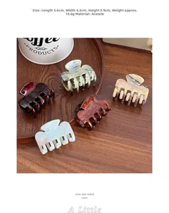 Detailed view of five marble acetate hair claws in various colors on a wooden tray