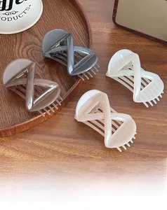 Detailed view of four cross-shaped resin hair claws in assorted Morandi colors on a tray