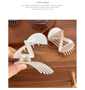 Detail view of large cross-bow hair clips in cream and khaki with matte finish