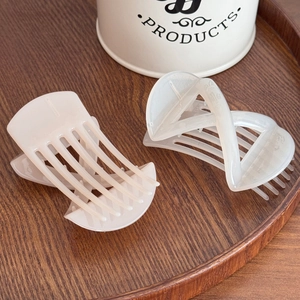 Minimalist cream and pink hair claw clips set on a dark wood tray in lifestyle shot