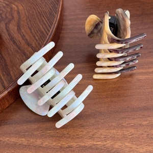 Elegant tortoiseshell and pearlescent acetate hair claws set on a dark wood background