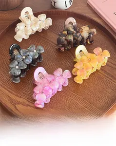Detailed macro shot of 5-piece floral acetate hair claws with rhinestones in a tray