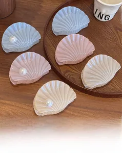 Vue détaillée de pinces à cheveux en forme de coquillage pastel avec perles élégantes