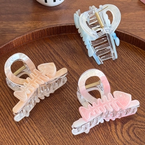 Three-piece set of colorful acetate fishbone hair claws with glitter on a wooden tray