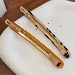 Minimalist leopard and amber resin barrette hair clips on a white ceramic plate