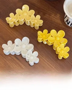 Gros plan de pinces à cheveux fleurs de frangipanier jaunes et blanches sur bois rustique