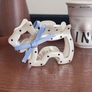 Pince à cheveux motif chien à pois avec nœud bleu sur un plateau près d'une tasse de café