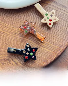 Detailed close-up of acetate star hair clips with colorful crystals on a wooden tray