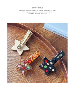 Detailed close-up of acetate star hair clips with colorful rhinestones in a wooden tray