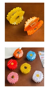 Close-up of colorful daisy-shaped acetate hair claws with a pearl finish and metal spring