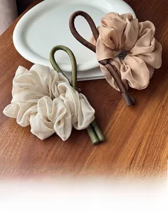 Macro detail of beige and pink chiffon pleated scrunchies with leather accents