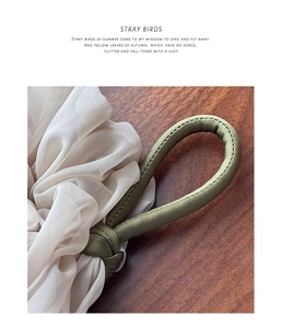 Close-up of olive green ring with cream sheer tulle pleats on a dark wood background