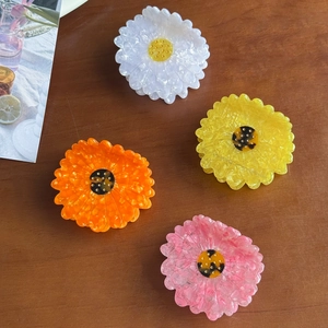 Charming acetate daisy hair claws in white yellow orange and pink on a rustic wood table