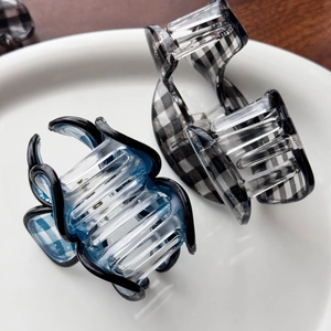 Set di mollette per capelli a scacchi blu e neri in resina lucida su un piatto