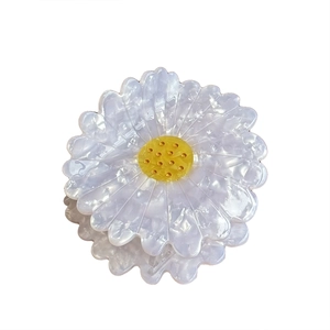 Elegant daisy hair claw clip made of white acetate with a pearlescent finish and yellow center