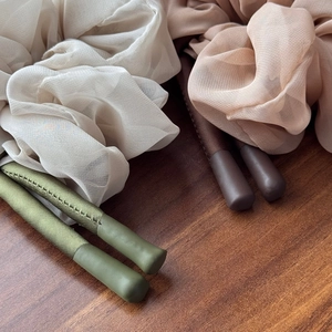Elegant tulle bow scrunchies and hairbands in beige and pink displayed on a wood background