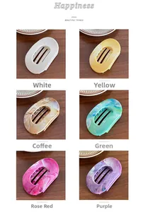 Flat oval hair claw clips in ink marble pattern with six assorted colors on wood surface