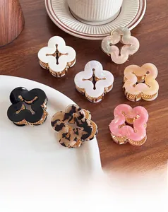 Detail showing various colors of clover-shaped hair claw clips on a wooden tabletop