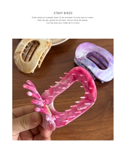 Close-up of stylish marble texture hair claws in rose pink, purple, and beige colors