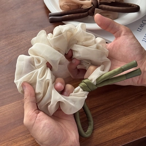 Elegant beige chiffon scrunchie with dark green ribbon streamers for women's hair styling