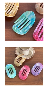 Detail shot of flat marble texture hair claws in various colors on wooden surface
