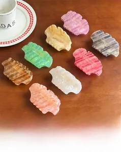 Flat lay of eight colorful marble pattern acetate hair claws on a rustic wooden desk