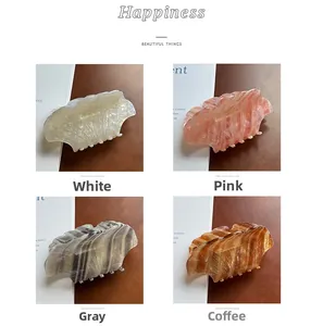 Detailed comparison of four shell-shaped acetate hair claws in white, pink, grey and amber