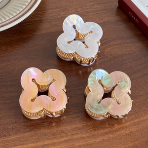 Elegant floral acrylic hair clips in iridescent white, coral, and green on wooden desk