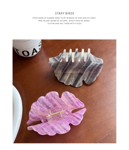Detailed view of large acetate hair claws with marble and glitter textures on wood