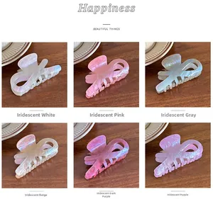 Selection of glossy ribbon hair claws in six colors shown on a dark wooden surface