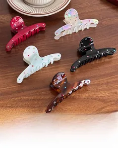 Detail view of five colored acetate hair claws with sparkling rhinestones on wood