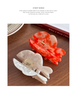 Detail of marble acetate hair claw clips with strong metal spring on a wooden desk